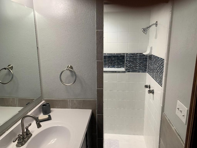 bathroom featuring tiled shower and vanity