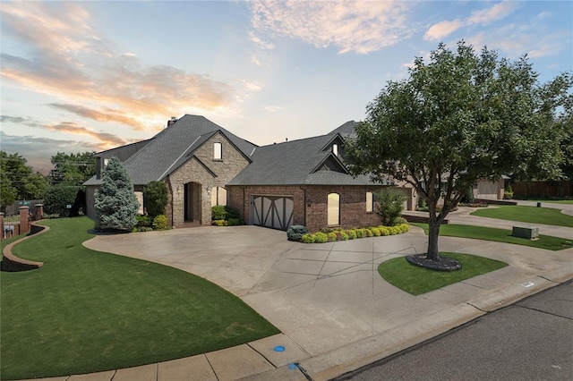 french country home with a lawn and a garage