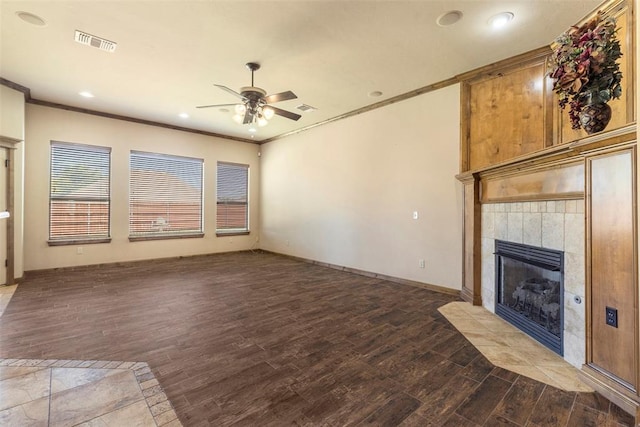 unfurnished living room featuring a tile fireplace, hardwood / wood-style flooring, ceiling fan, and crown molding