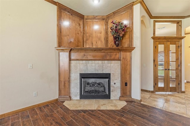 room details featuring a fireplace, french doors, hardwood / wood-style flooring, and crown molding