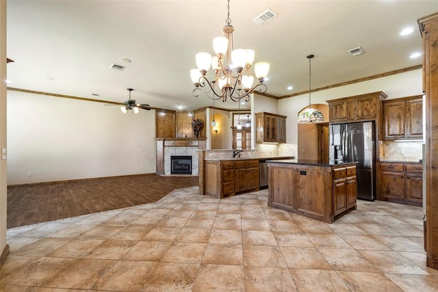 kitchen with decorative backsplash, ceiling fan with notable chandelier, stainless steel appliances, a tile fireplace, and decorative light fixtures