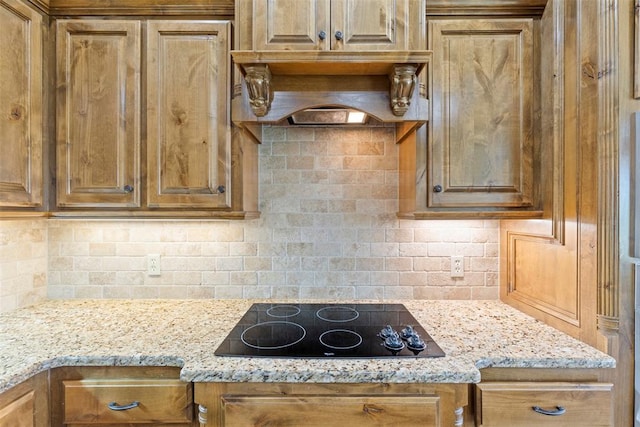 kitchen with light stone countertops, black electric cooktop, and tasteful backsplash