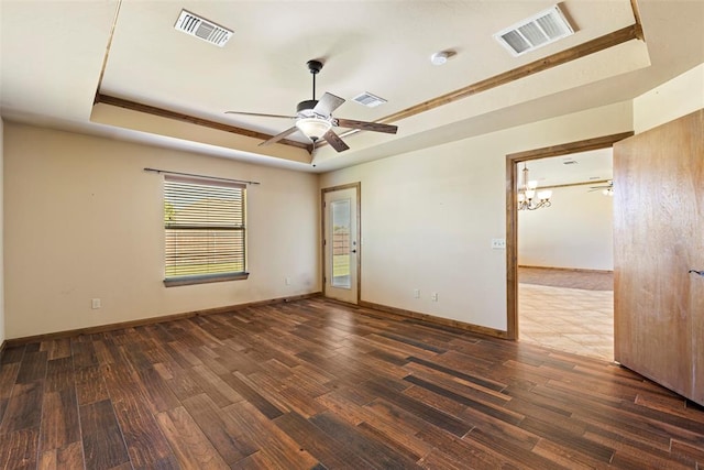 unfurnished room featuring a chandelier, dark hardwood / wood-style floors, and a raised ceiling