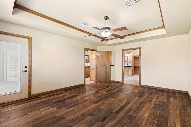 spare room featuring a raised ceiling, ceiling fan, a healthy amount of sunlight, and dark hardwood / wood-style floors