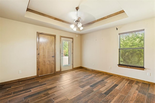 spare room featuring a raised ceiling, ceiling fan, and dark hardwood / wood-style flooring