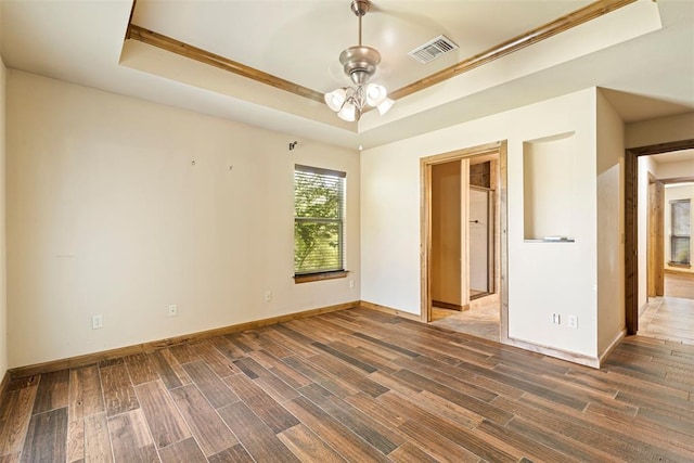 unfurnished room with a tray ceiling, ceiling fan, and dark hardwood / wood-style floors