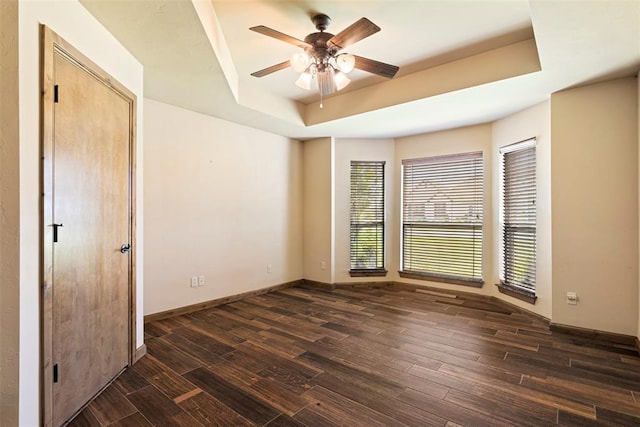 unfurnished room with dark hardwood / wood-style floors, ceiling fan, and a tray ceiling