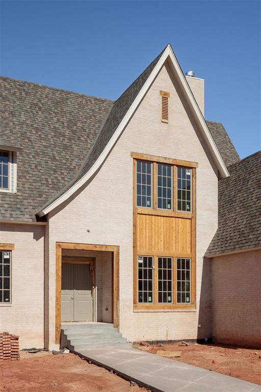 view of front of home with a shingled roof, a chimney, and brick siding