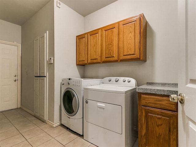 clothes washing area with cabinets, light tile patterned floors, and separate washer and dryer