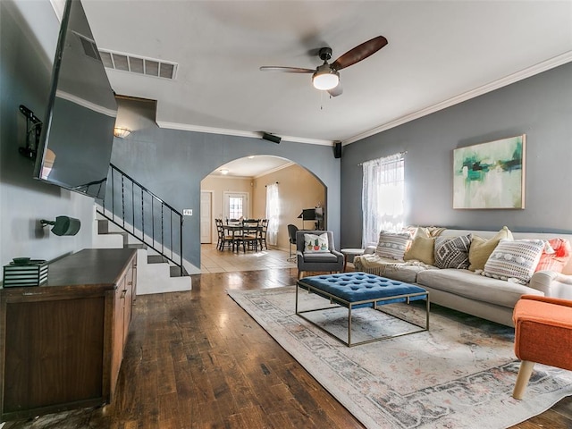 living room with crown molding, ceiling fan, and dark wood-type flooring