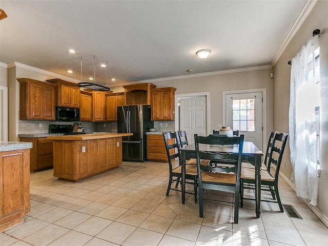 kitchen with a center island, crown molding, decorative backsplash, light tile patterned floors, and black appliances