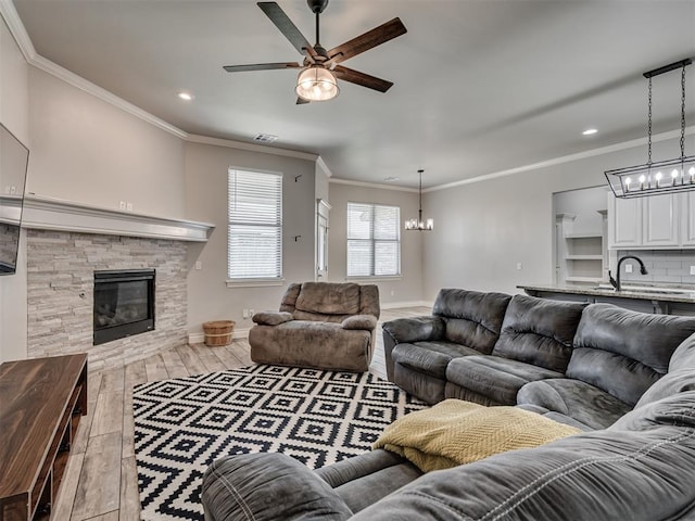 living room with light hardwood / wood-style floors, sink, ornamental molding, and a fireplace