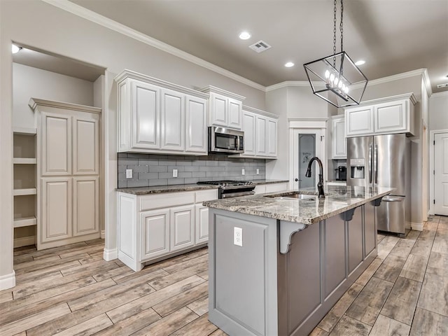 kitchen featuring light stone countertops, stainless steel appliances, sink, a center island with sink, and white cabinets