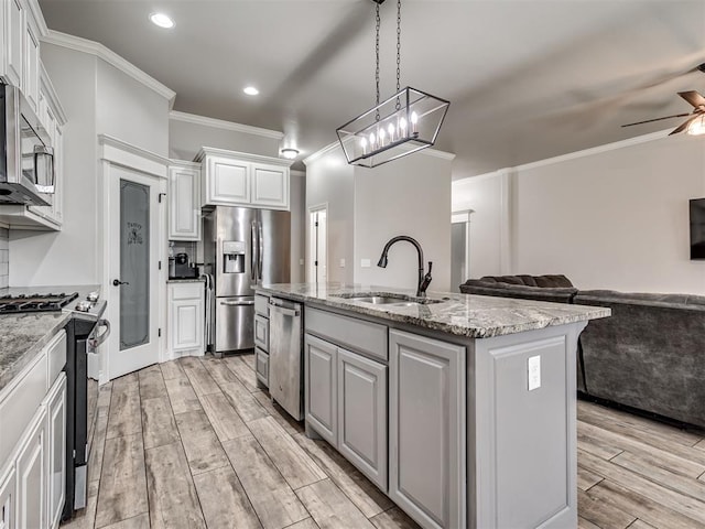 kitchen with sink, an island with sink, stainless steel appliances, and light wood-type flooring