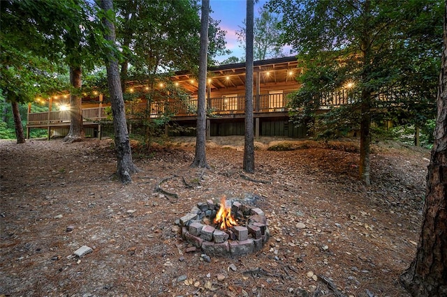 yard at dusk featuring a wooden deck and a fire pit