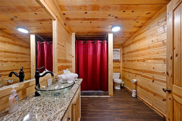 bathroom featuring wood walls, vanity, wood-type flooring, and vaulted ceiling