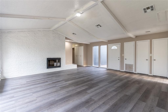 unfurnished living room with a fireplace, hardwood / wood-style floors, lofted ceiling with beams, and a textured ceiling