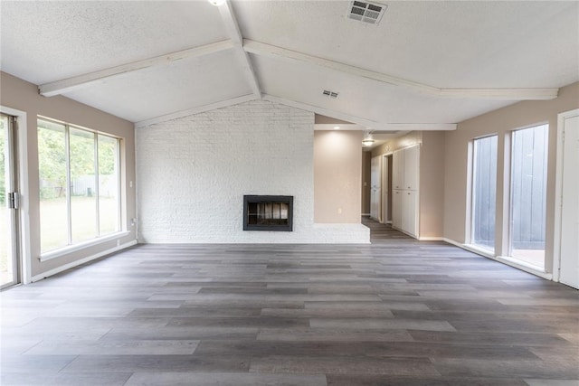 unfurnished living room with vaulted ceiling with beams, a large fireplace, dark wood-type flooring, and a textured ceiling