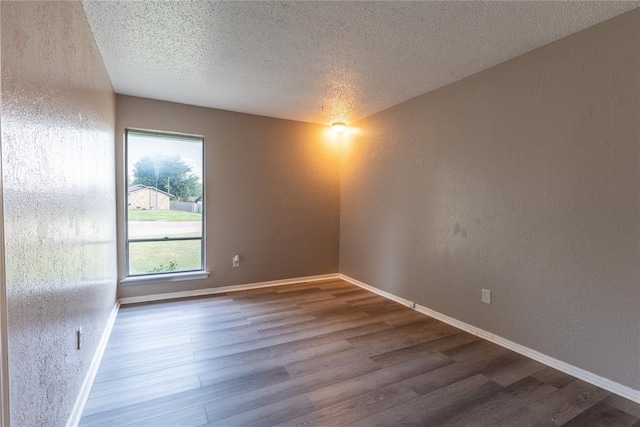 empty room featuring wood-type flooring and a textured ceiling