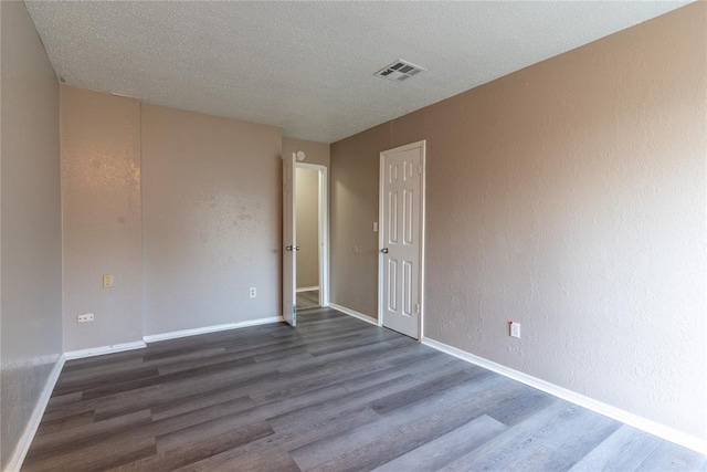 empty room featuring a textured ceiling and dark hardwood / wood-style flooring