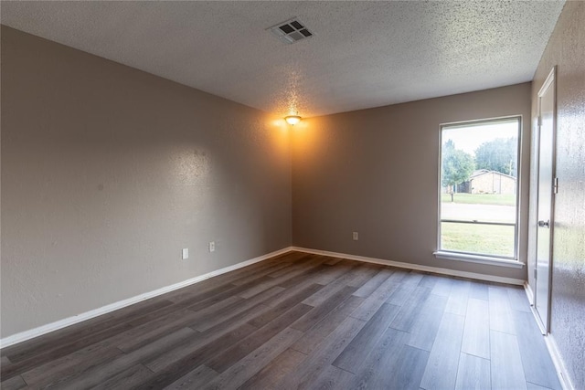 empty room featuring dark hardwood / wood-style floors and a textured ceiling