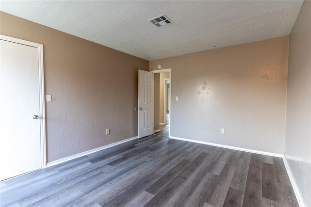 empty room with a textured ceiling and dark hardwood / wood-style flooring