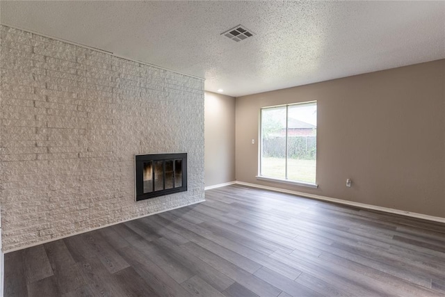 unfurnished living room with wood-type flooring, a large fireplace, and a textured ceiling