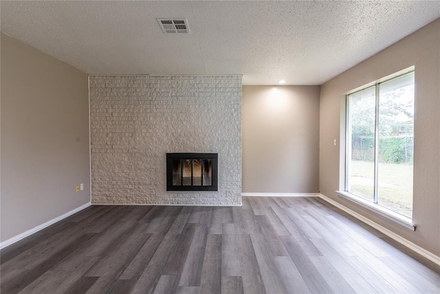 unfurnished living room with a textured ceiling, dark hardwood / wood-style flooring, and plenty of natural light