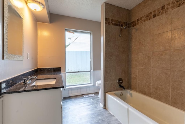 full bathroom featuring vanity, toilet, a textured ceiling, and tiled shower / bath