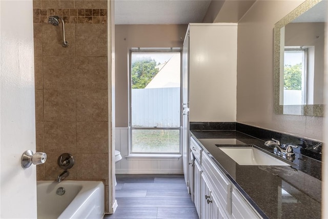 bathroom with hardwood / wood-style floors, vanity, and tiled shower / bath