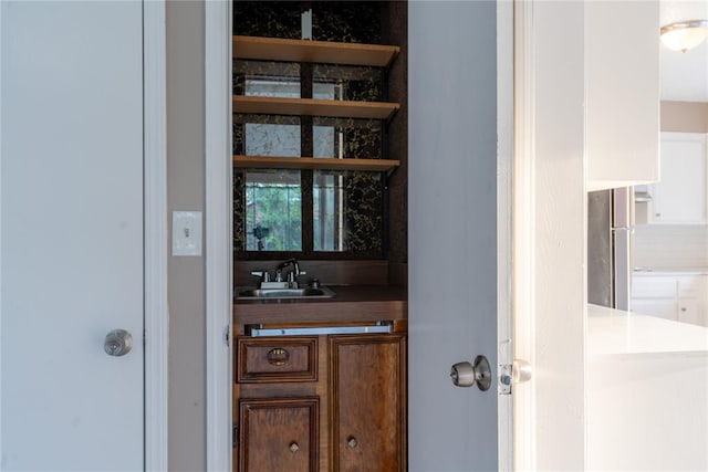 bar featuring stainless steel refrigerator and sink