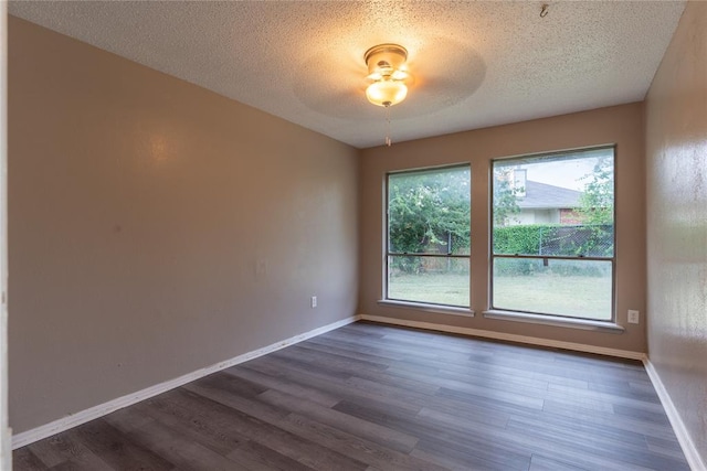 empty room featuring ceiling fan, dark wood-type flooring, and a textured ceiling