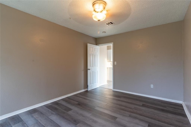 spare room featuring a textured ceiling and dark hardwood / wood-style floors