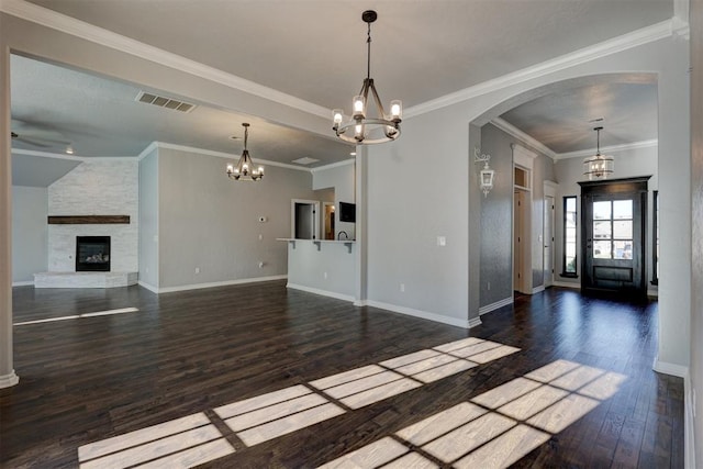 unfurnished living room featuring a stone fireplace, dark hardwood / wood-style flooring, ornamental molding, and a chandelier