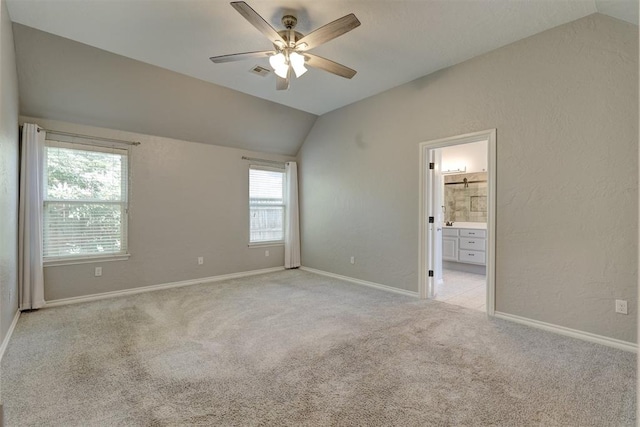 unfurnished bedroom featuring light carpet, connected bathroom, ceiling fan, and lofted ceiling