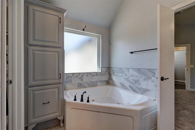 bathroom with a bath and vaulted ceiling