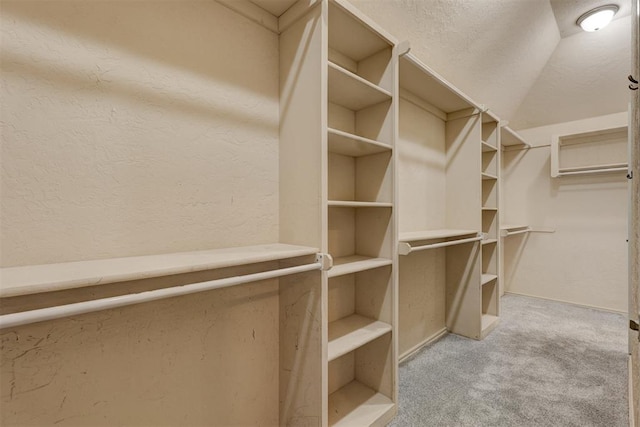 spacious closet with light colored carpet and vaulted ceiling