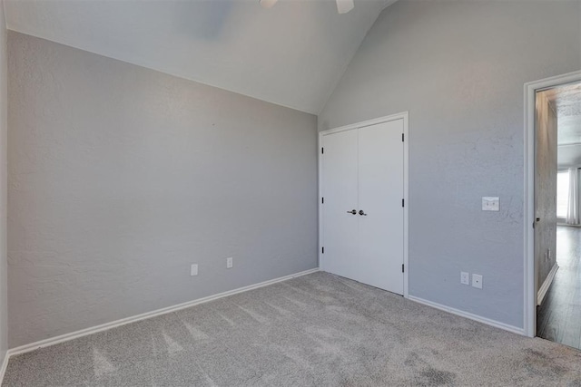 unfurnished bedroom featuring ceiling fan, a closet, light colored carpet, and lofted ceiling