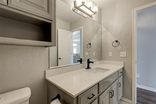 bathroom with hardwood / wood-style floors, vanity, and toilet