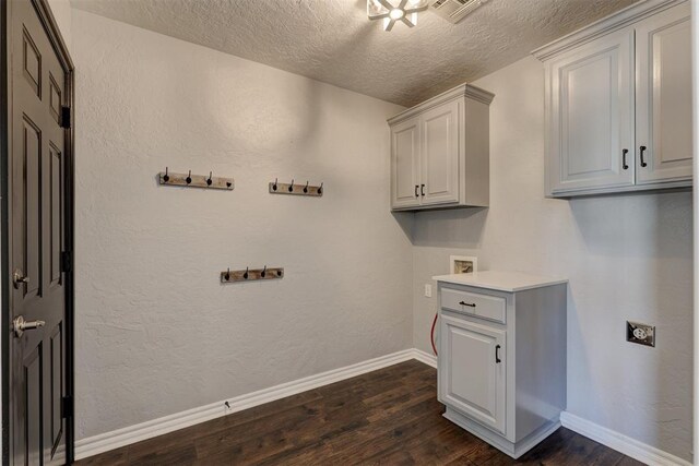 clothes washing area with cabinets, hookup for a washing machine, dark hardwood / wood-style flooring, a textured ceiling, and electric dryer hookup