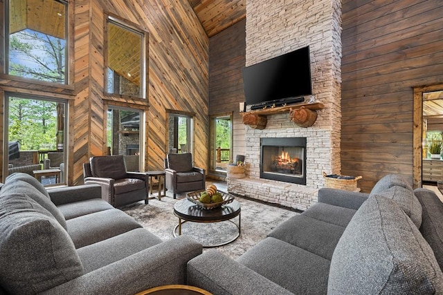 living room featuring a stone fireplace, wood walls, and a towering ceiling