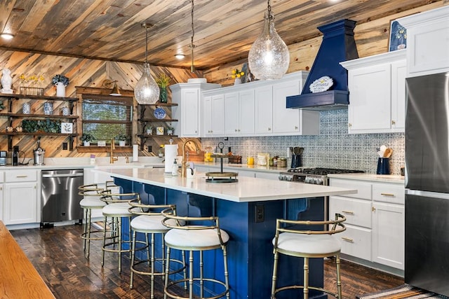 kitchen featuring white cabinets, a breakfast bar, wood walls, and stainless steel appliances