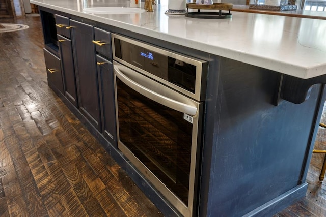 kitchen featuring a kitchen breakfast bar, dark hardwood / wood-style flooring, and stainless steel oven