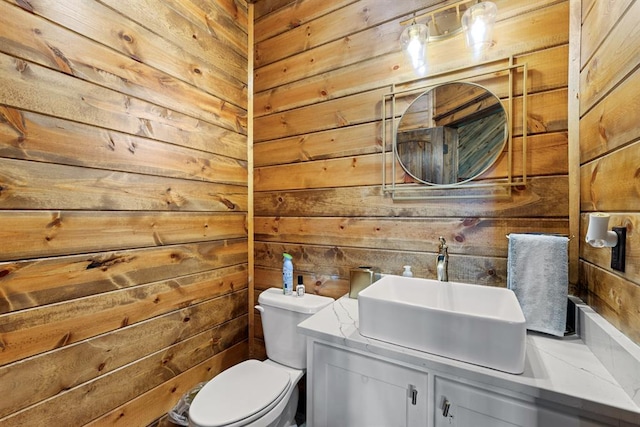 bathroom featuring vanity, toilet, and wood walls