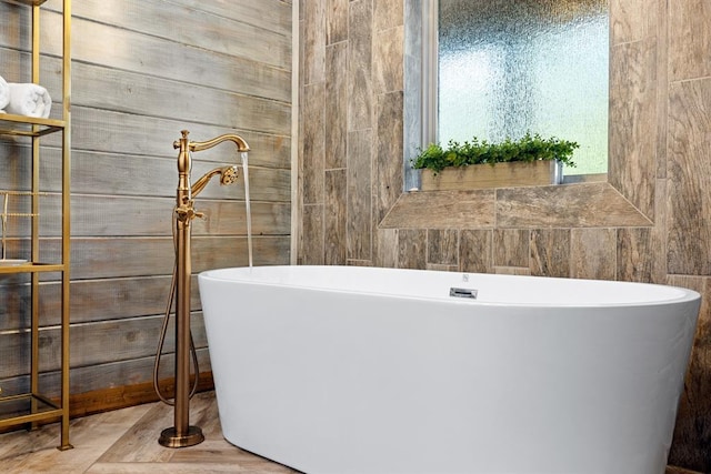 bathroom with a bathtub and wood walls