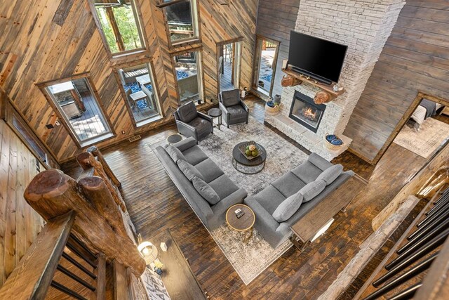 living room featuring wood walls, dark hardwood / wood-style flooring, a towering ceiling, and a fireplace