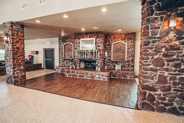 unfurnished living room with wood-type flooring and a stone fireplace