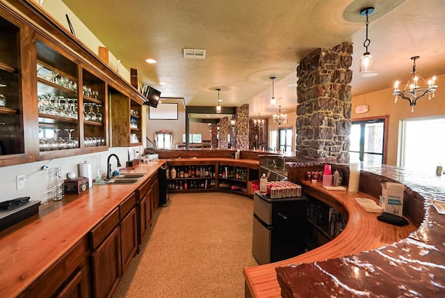 bar featuring dark brown cabinetry, sink, a chandelier, and decorative light fixtures
