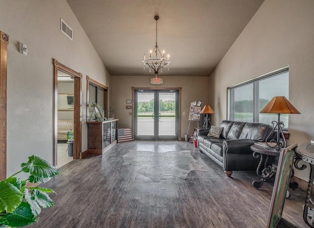 interior space with french doors, dark wood-type flooring, vaulted ceiling, and an inviting chandelier