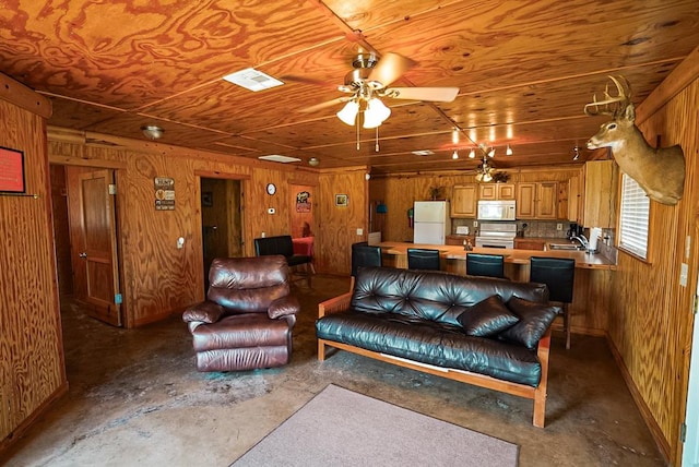 living room featuring ceiling fan, wooden walls, and concrete floors